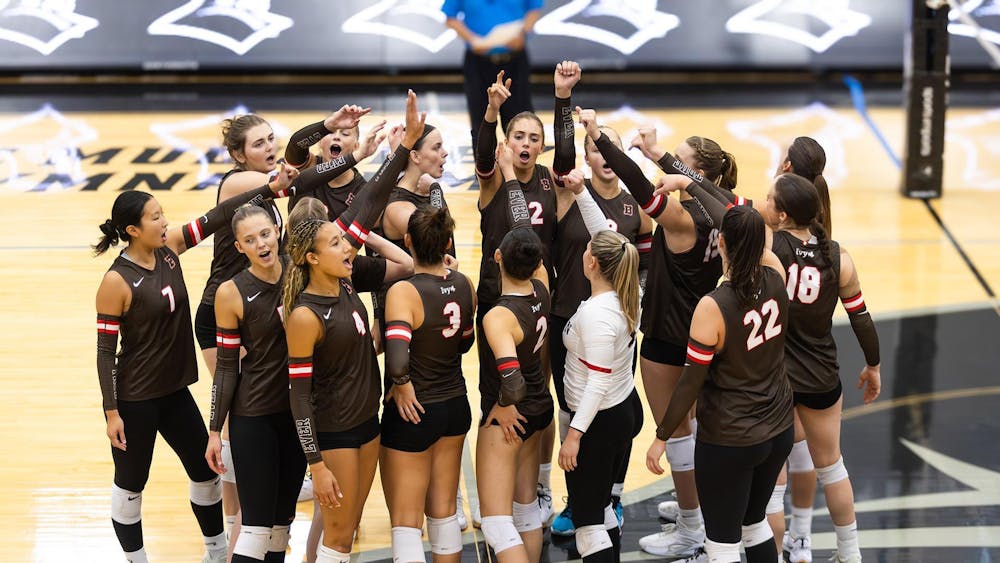 Photo of the women’s volleyball team breaking after a team huddle.