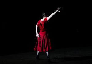 A woman in a red dress from behind, framed by a black background.