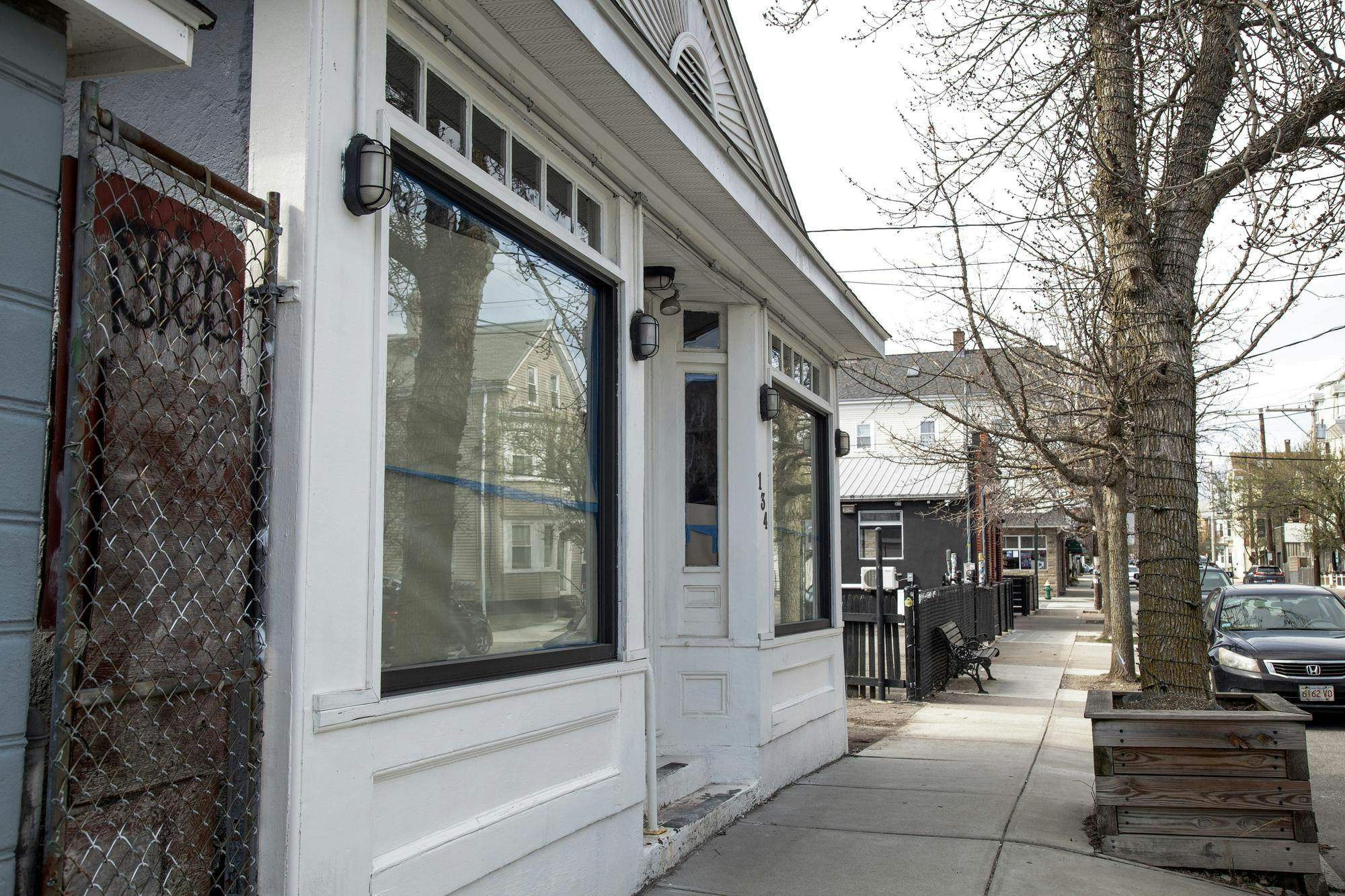 A photo showing a white house along a sidewalk with the windows and door covered by paper. 