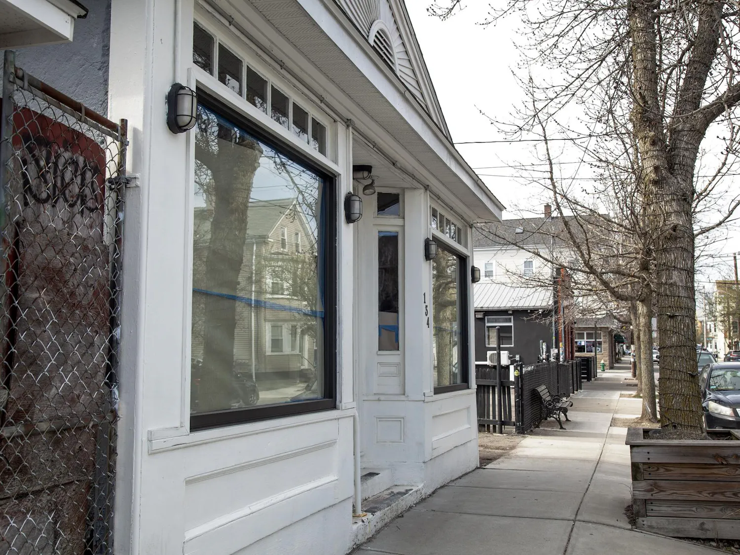 A photo showing a white house along a sidewalk with the windows and door covered by paper.
