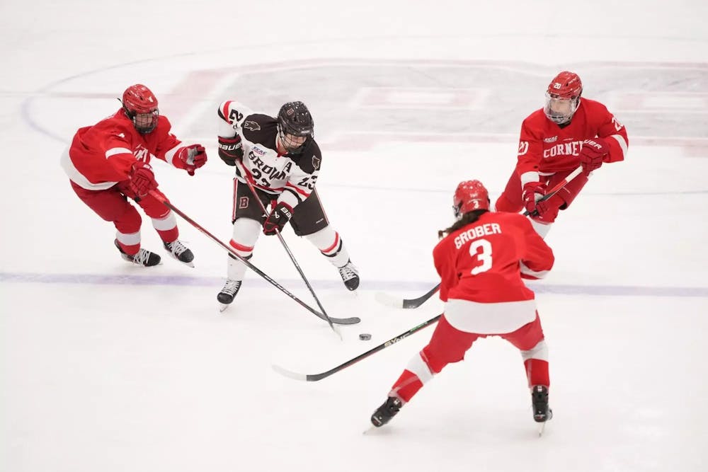 A Brown hockey player maneuvers the puck as three Cornell players surround her and attempt to take the puck at Brown University's Meehan Auditorium.  