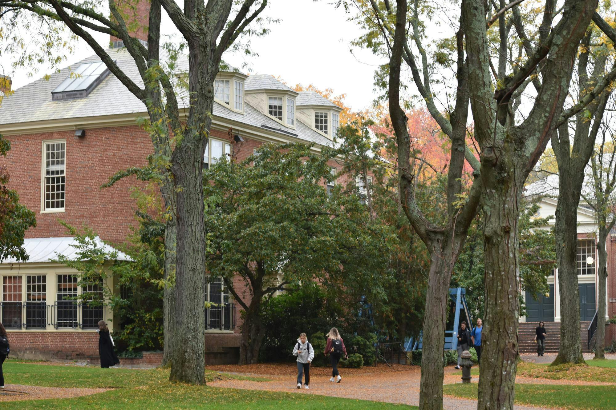 A photo of Patriot Court in early fall. Students are walking along the paths and the leaves on some trees are turning orange. 