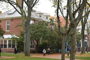 A photo of Patriot Court in early fall. Students are walking along the paths and the leaves on some trees are turning orange. 