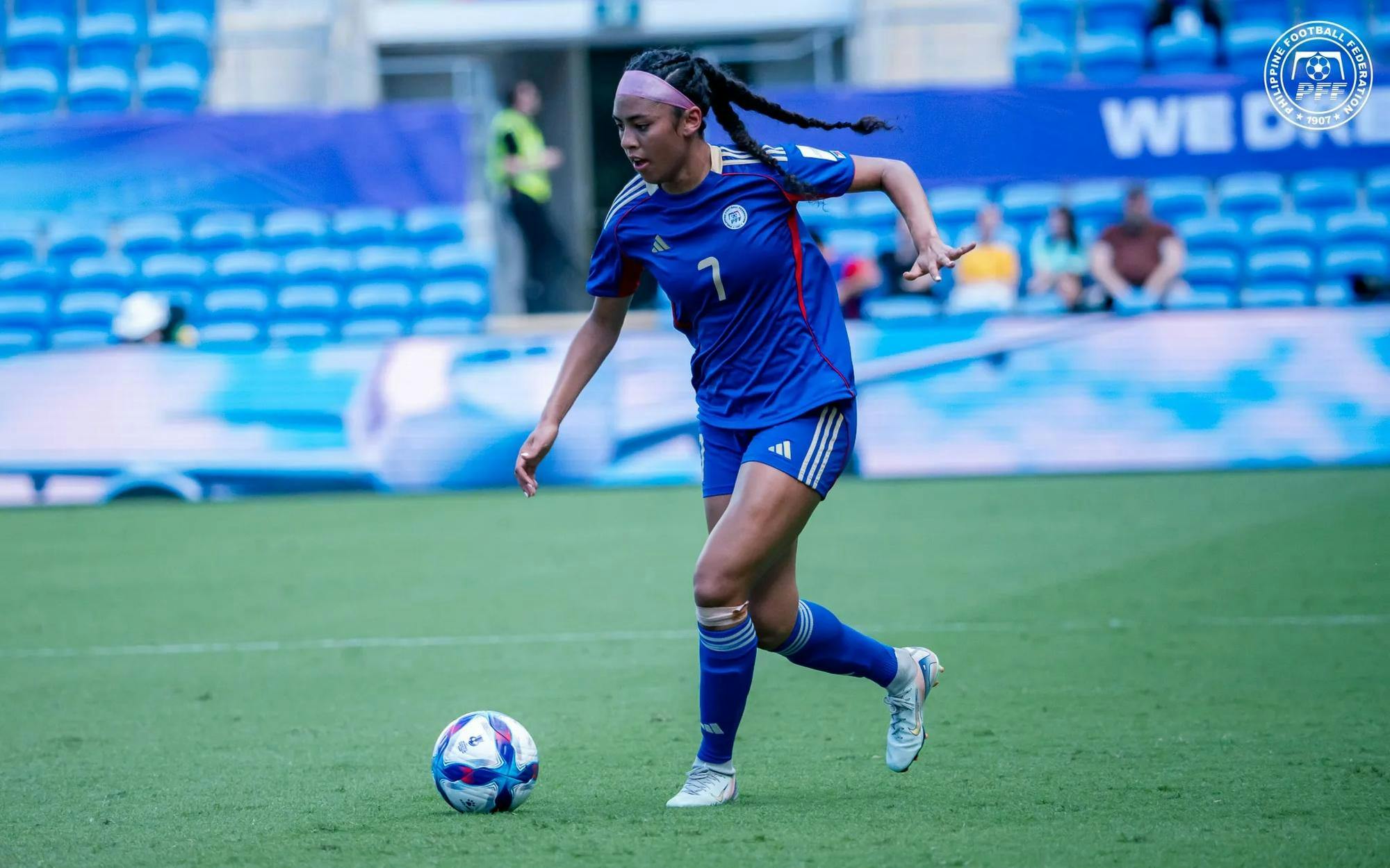 Jael-Marie Guy in an all-blue soccer uniform dribbling a soccer ball. 