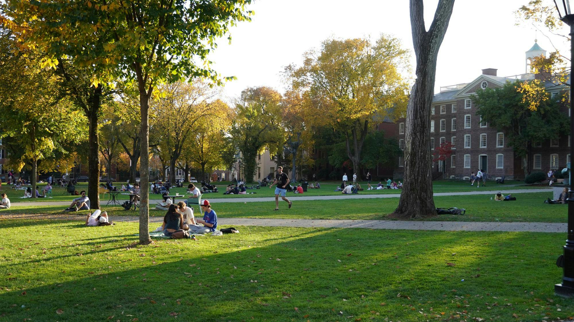 Students sit in the sunlight on the Main Green.