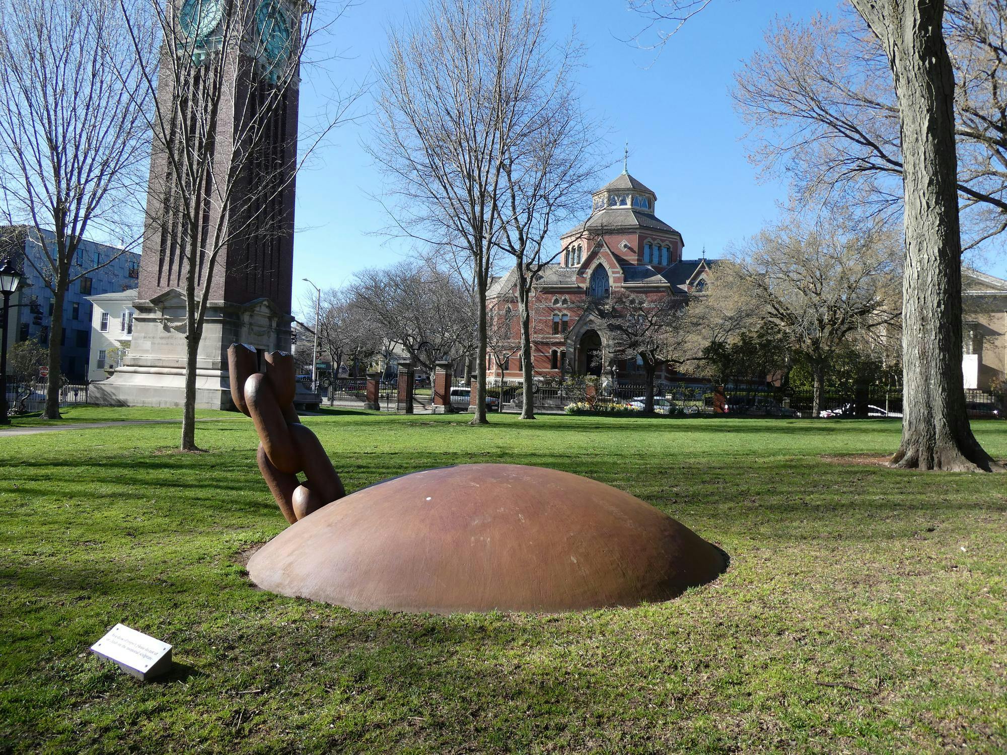 An image of the quiet green at Brown, facing a large ball and chain structure and clock tower.