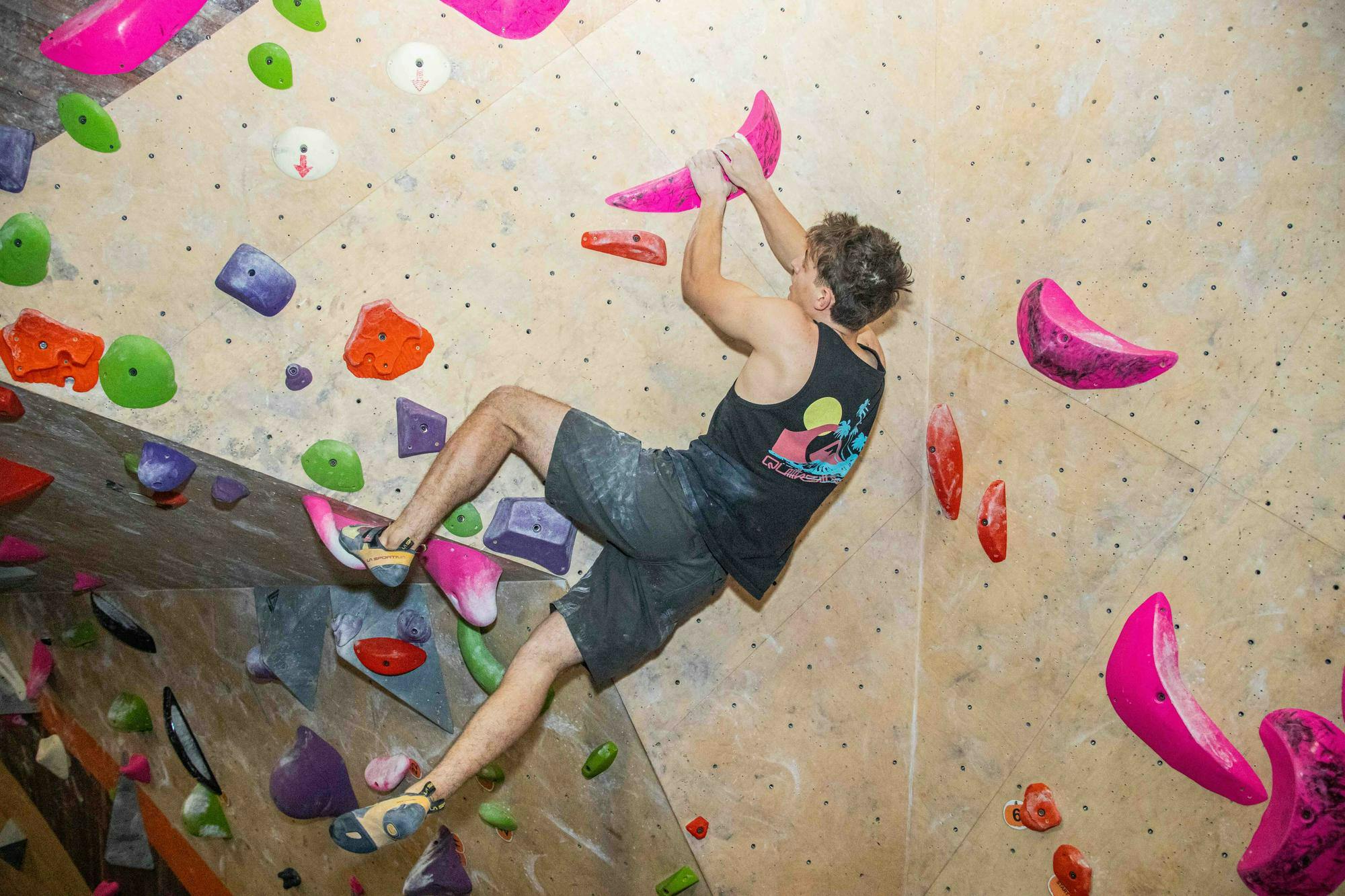 Photo of a man climbing on a multicolored rock wall