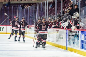 Photo of members of the Brown Women’s Hockey team high-fiving their teammates on an ice rink.