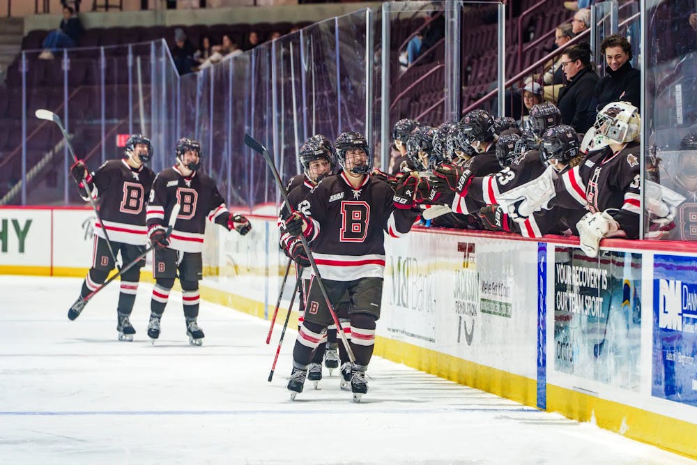 Photo of members of the Brown Women’s Hockey team high-fiving their teammates on an ice rink.