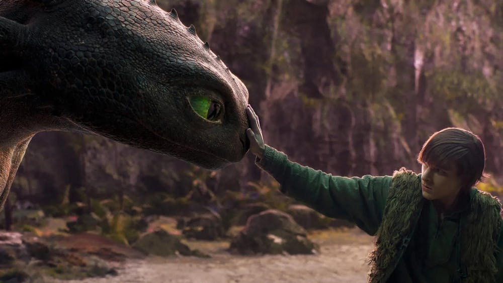 Photo of a boy gently placing his hand on the nose of a black dragon with green eyes.