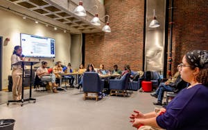 Photo of the Graduate Student Council meeting in April, where a group of students sit around a speaker and TV.