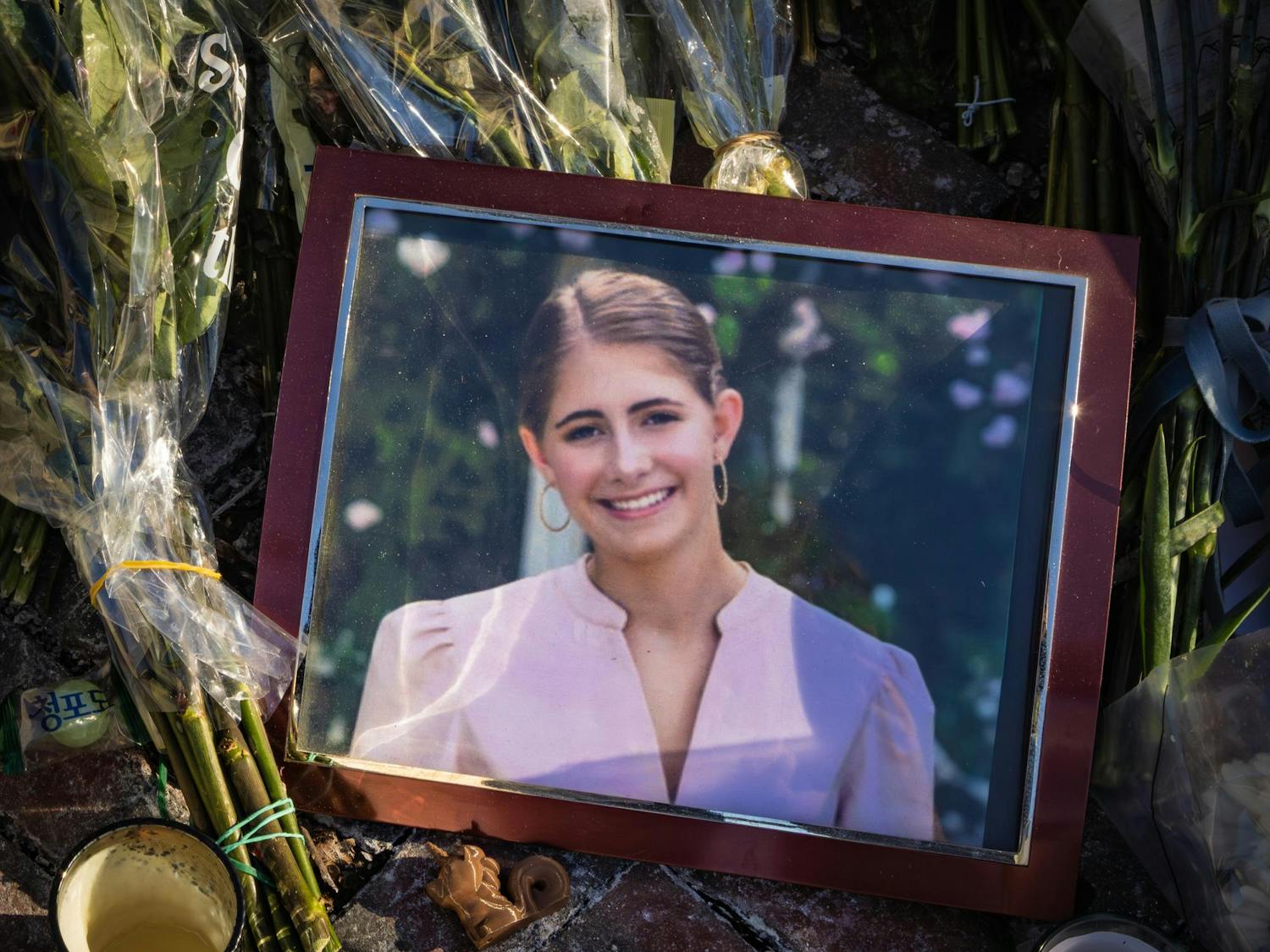 A picture frame of a smiling girl sits on top of bouquets of flowers.