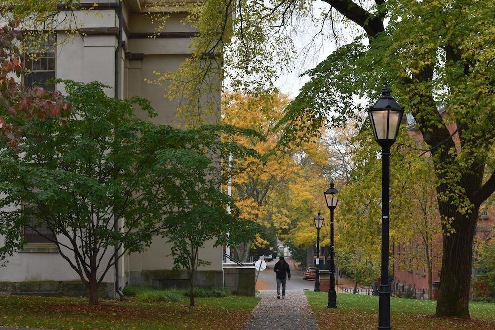 A man walks through a tree-lined pathway on Brown University's Quiet Green.