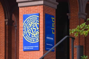 A column of a brick building with a blue banner in the front that features a yellow RISD logo and a banner on the side that features “risd” in yellow lettering.