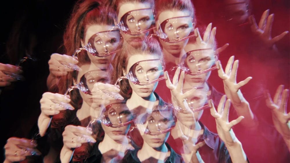Image of multiple instances of a woman holding up a wine glass over her face, the reflection distorting her eyes, replicated in a kaleidoscopic effect. 