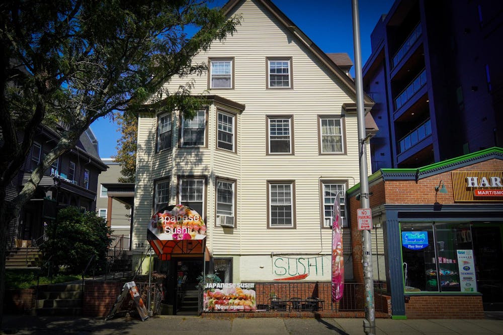 Photo of the front of a cream-colored home with a Japanese Sushi restaurant on the bottom floor.