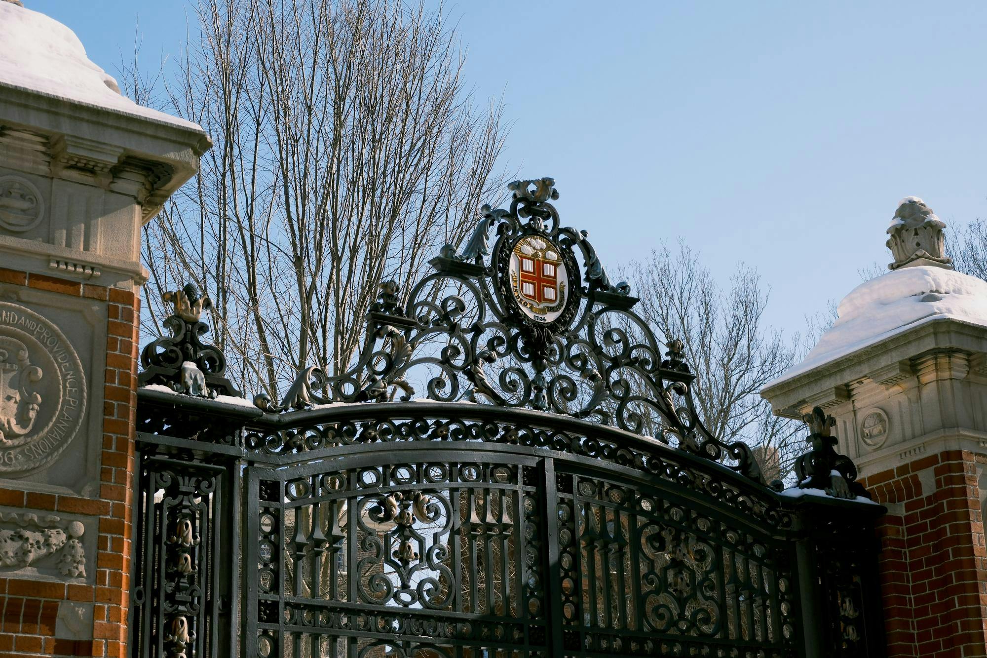 A photo of Van Wickle Gates with a blue sky, with snow on the side pillars of the gate.