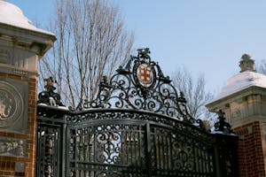 A photo of Van Wickle Gates with a blue sky, with snow on the side pillars of the gate.