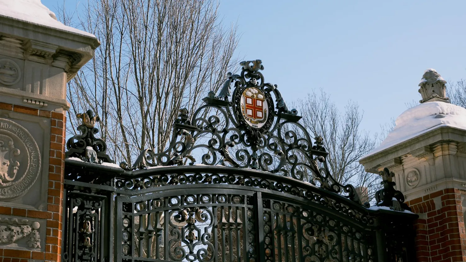 A photo of Van Wickle Gates with a blue sky, with snow on the side pillars of the gate.