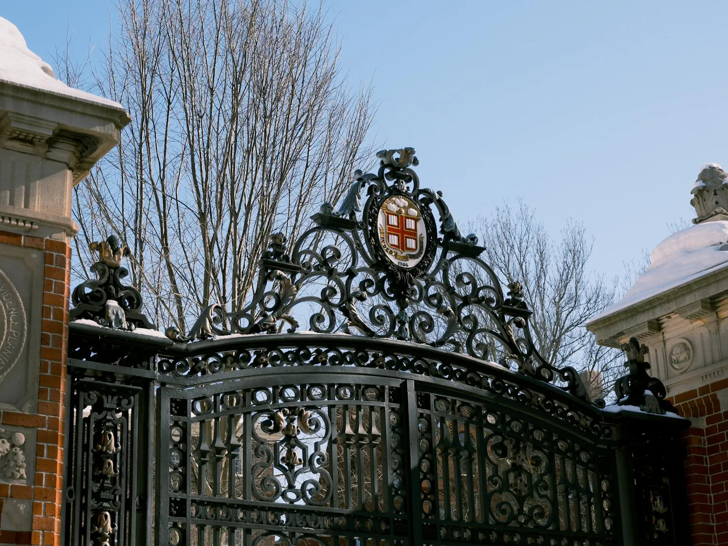 A photo of Van Wickle Gates with a blue sky, with snow on the side pillars of the gate.