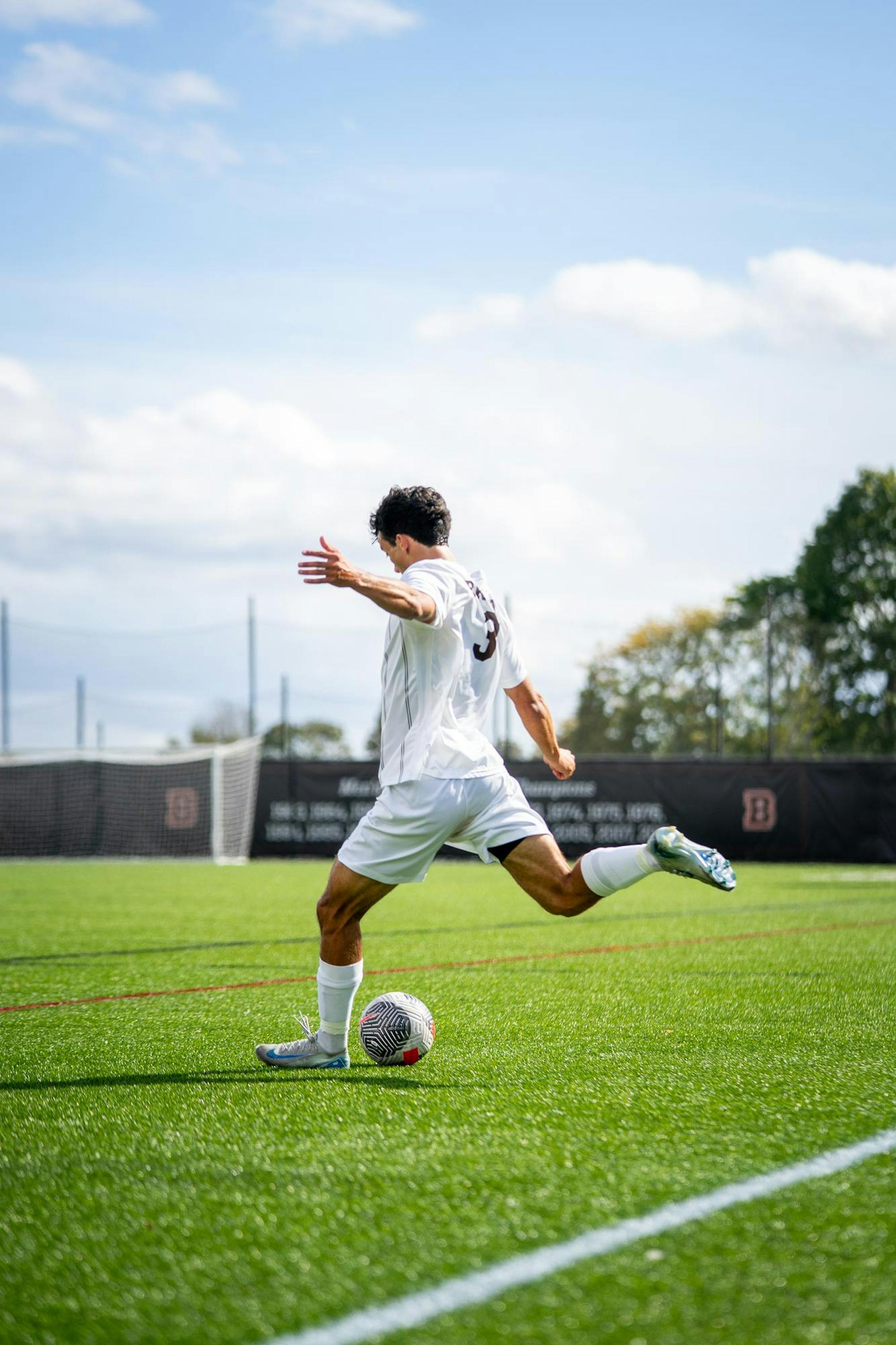 Photo of Greyson Mitchell, Men's Soccer number 3, kicking a soccer ball onto the field.