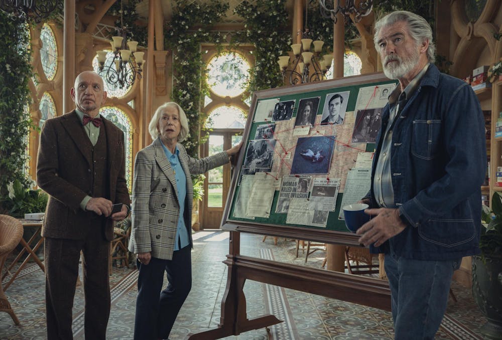 A frame from The Thursday Murder Club, showing three of the show's lead characters around a bulletin board of evidence.