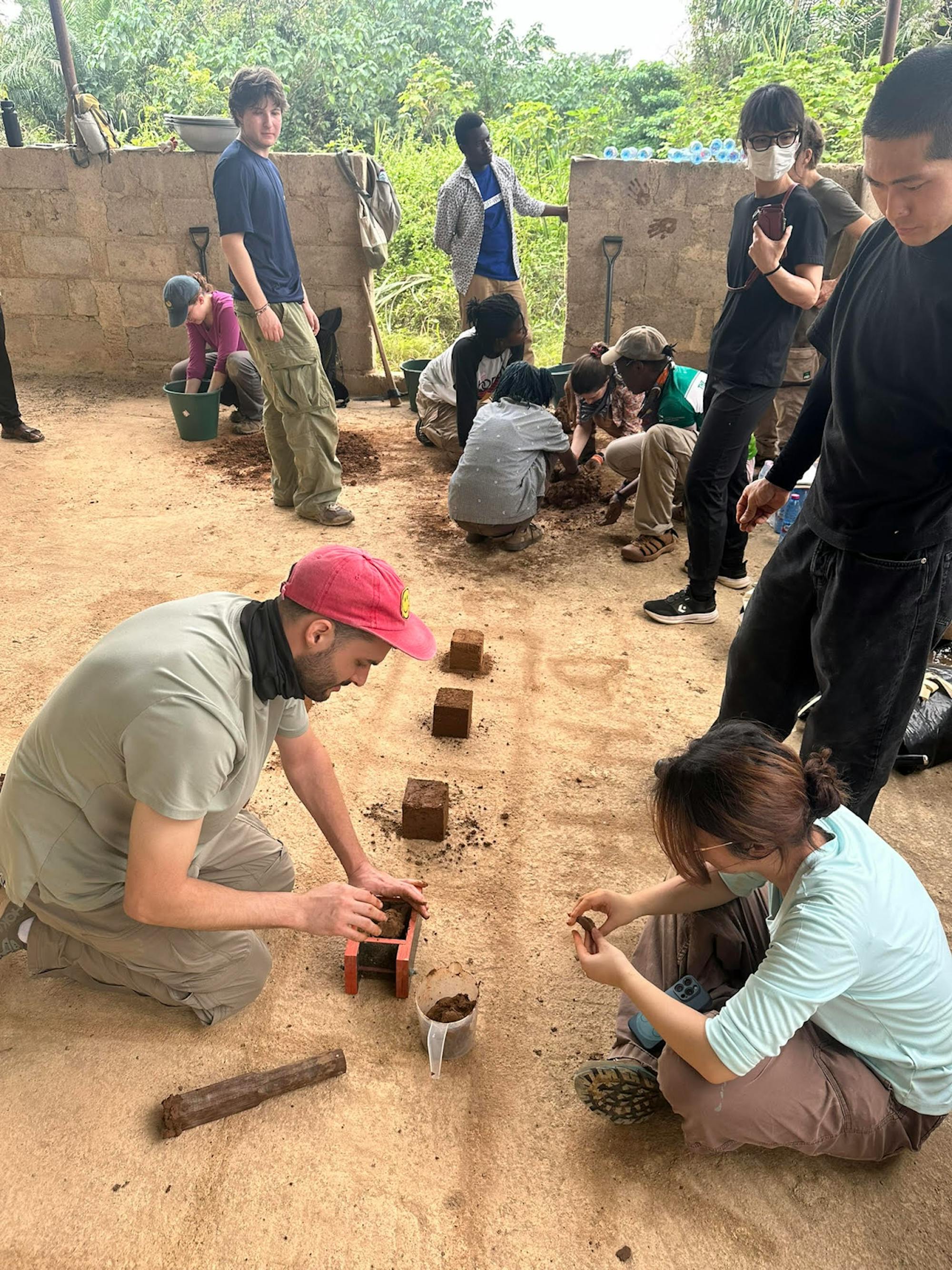 Photo of Brown RISD Dual Degree sitting on the floor making bricks with clay in Ghana.