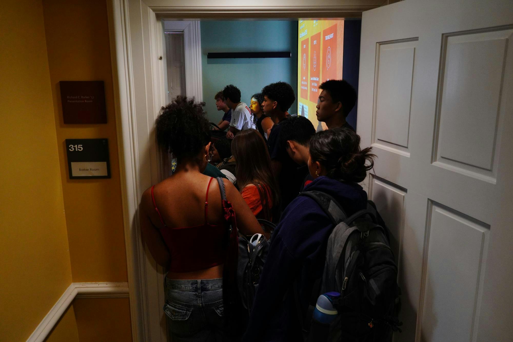 Photo of a group of students crowding a doorway leading to a packed classroom.