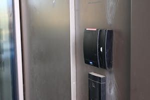 Photo of a black Brown card-swipe reader with a red light against a silver wall background.