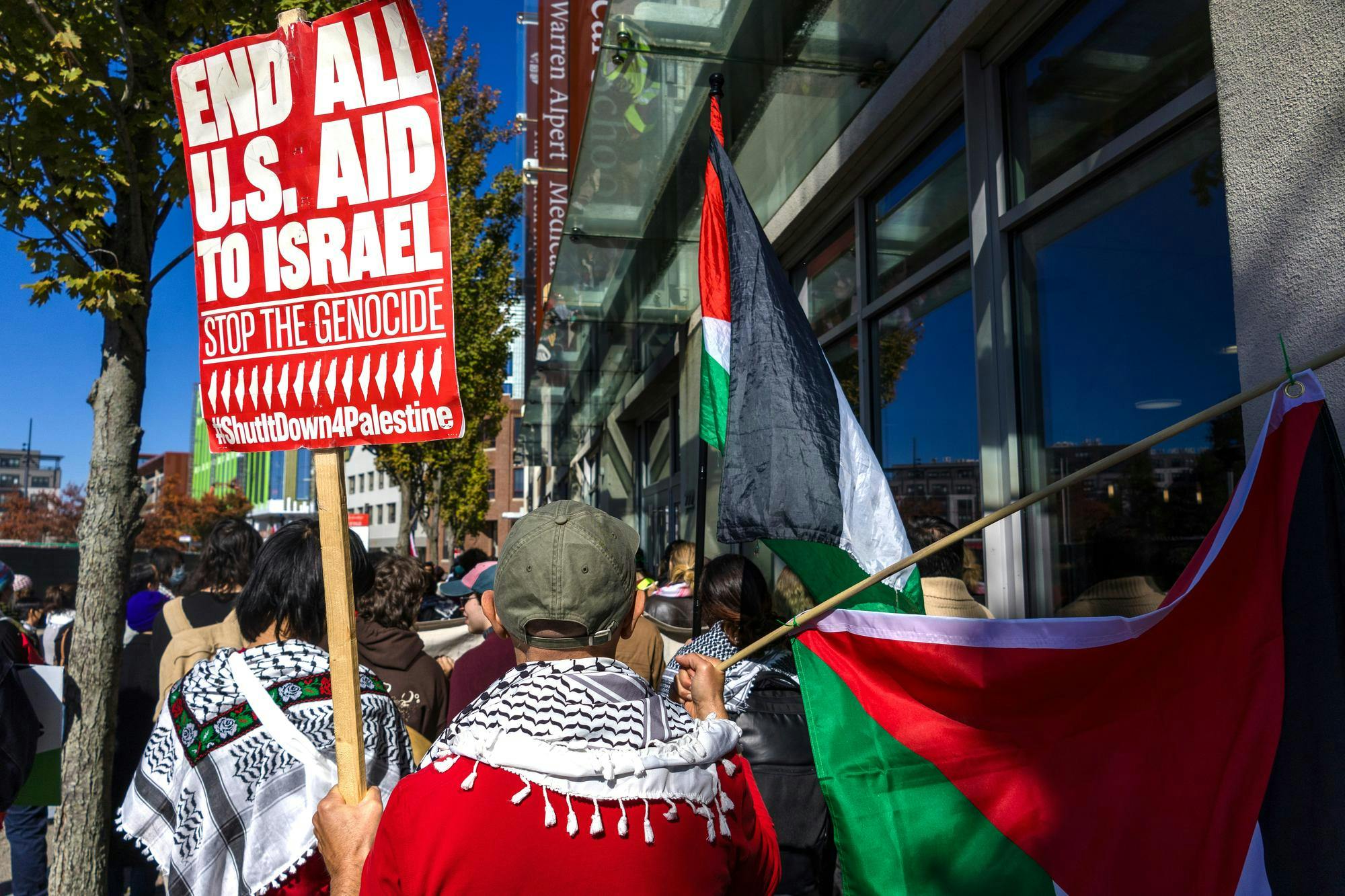 A student holds a sign reading "End all U.S. aid to Israel" in a pro-Palestine rally.