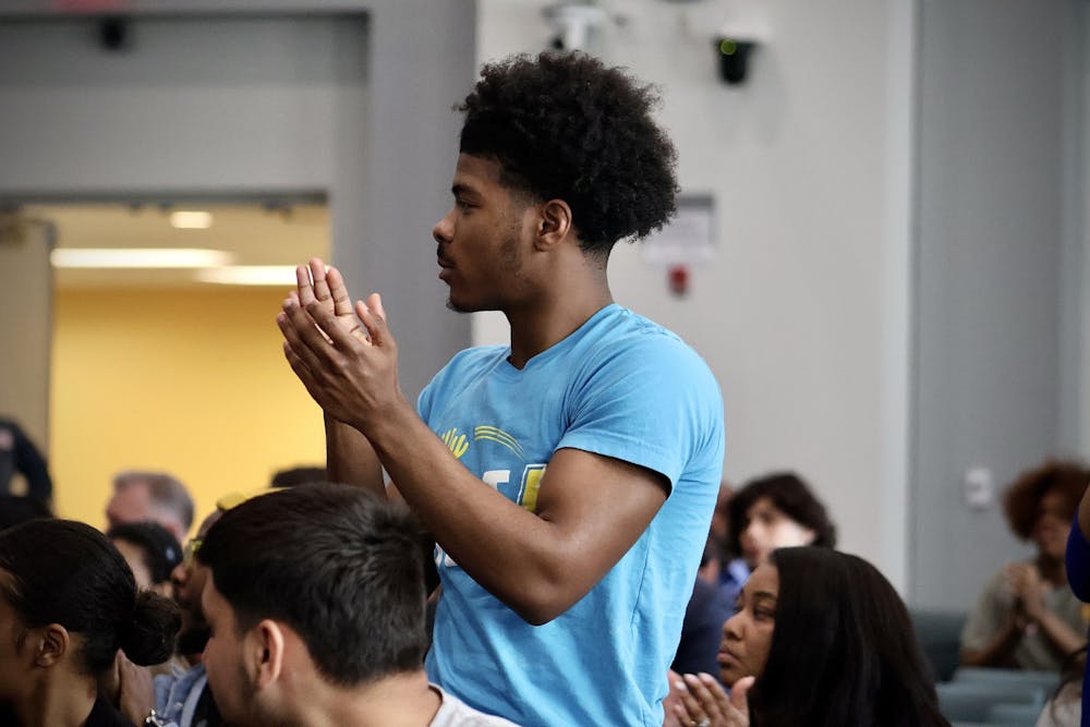 <p>PhillyBOLT member Milaj Robinson stands up, clapping,  for fellow youth members of PhillyBOLT at the Philly Youth Voices event surrounded by candidates for mayor and city council along with others | (Kasey Shamis/Bullhorn Photographer)</p>