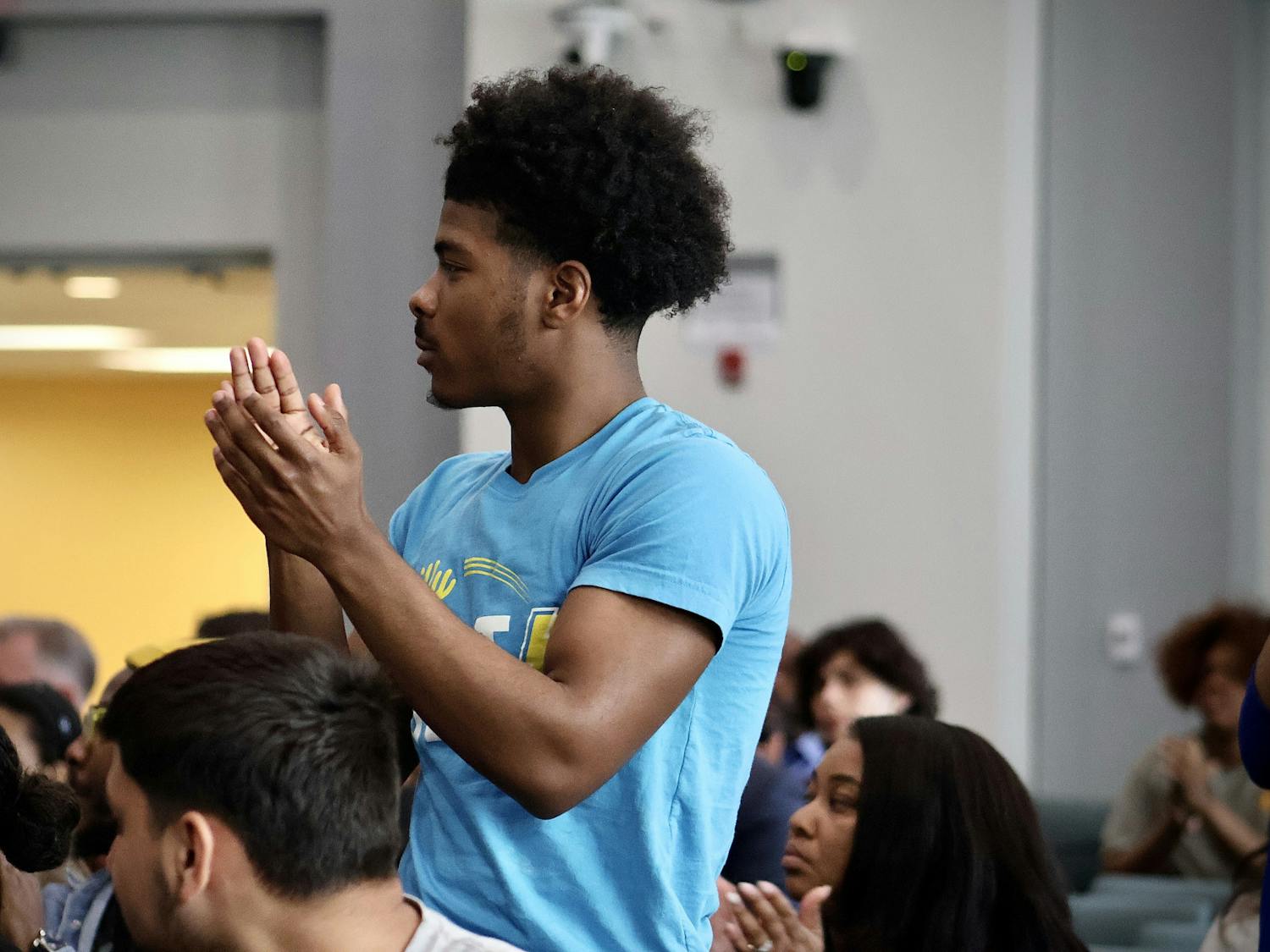 PhillyBOLT member Milaj Robinson stands up, clapping,  for fellow youth members of PhillyBOLT at the Philly Youth Voices event surrounded by candidates for mayor and city council along with others | (Kasey Shamis/Bullhorn Photographer)