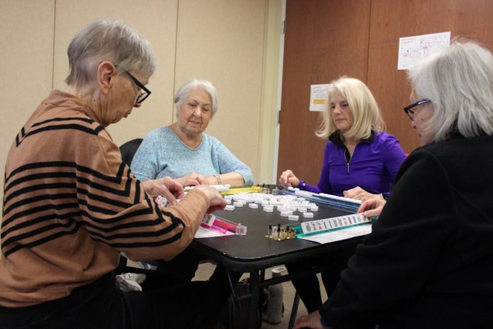 After lunch, a group of Surrey members engage in a mahjong game. Cards and board games are set up, and members are free to play. The National Academies of Sciences, Engineering, and Medicine reported that nearly one-fourth of adults aged 65 and older are considered to be socially isolated.
