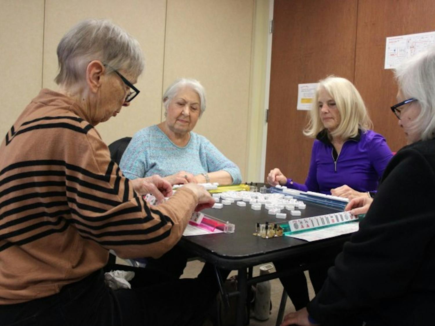 After lunch, a group of Surrey members engage in a mahjong game. Cards and board games are set up, and members are free to play. The National Academies of Sciences, Engineering, and Medicine reported that nearly one-fourth of adults aged 65 and older are considered to be socially isolated.