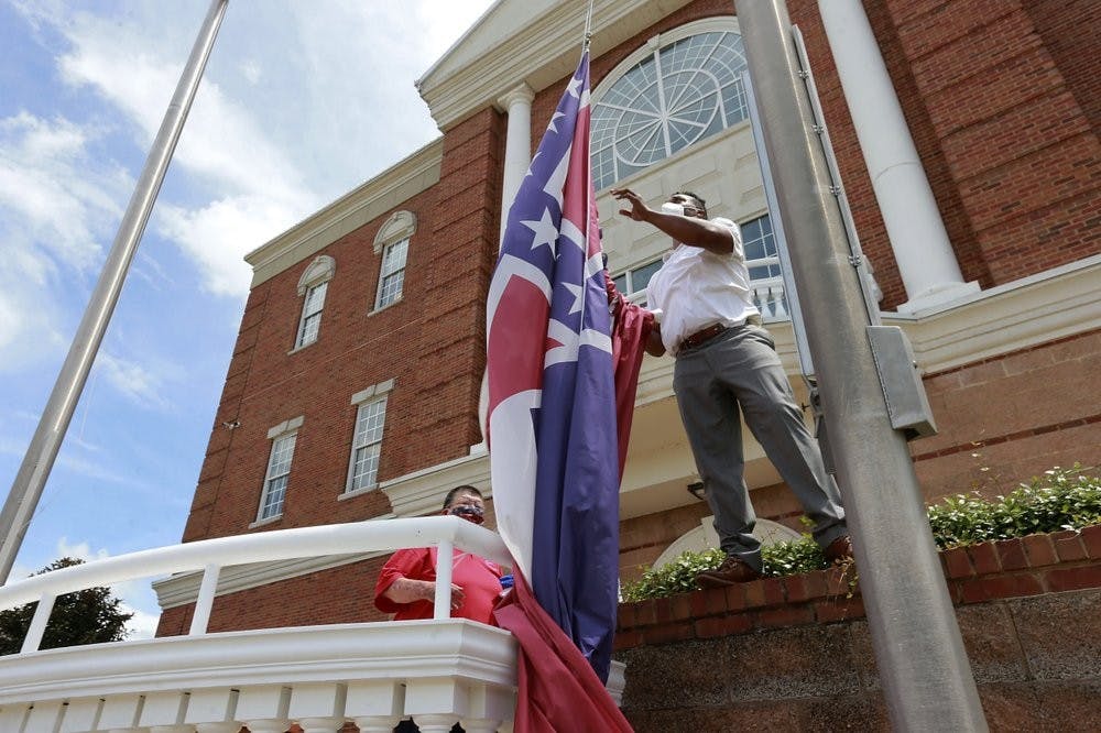 <p>City of Tupelo Community Outreach Coordinator Marcus Gary takes down the Mississippi state flag that flew over the City Hall of Tupelo one last time June 29, 2020. Mississippi is retiring the last state flag in the U.S. that includes the Confederate battle emblem. <strong>(Thomas Wells/The Northeast Mississippi Daily Journal via AP, File)</strong></p>