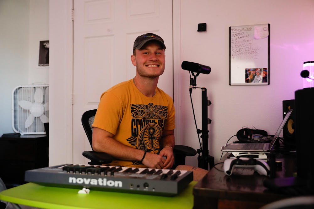 Fourth-year Ball State student Tommy West smiling while sitting at his home studio Oct. 22 at his apartment in Muncie, Ind. West has been creating R&B and pop music for three years now at Ball State. Andrew Berger, DN 
