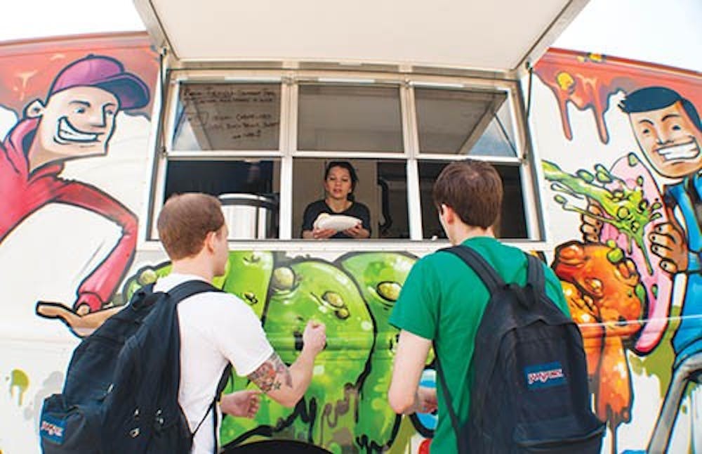 Slop on Top manager Christina McVay hands out food to Steven Putt, left, and Charlie Koers. The food truck, located next to Village Green Records, opened in March. DN PHOTO BOBBY ELLIS