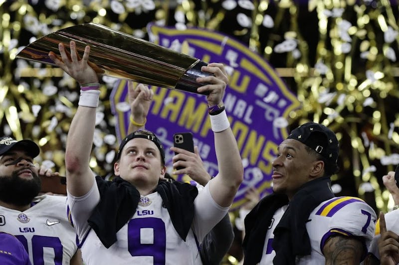 LSU quarterback Joe Burrow holds the trophy as safety Grant Delpit looks on after a NCAA College Football Playoff national championship game against Clemson, Jan. 13, 2020, in New Orleans. LSU won 42-25. (AP Photo/Sue Ogrocki)