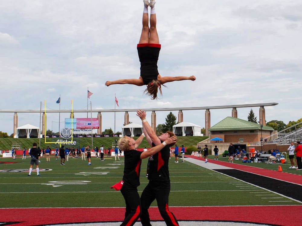 Second-year nursing major Titus Hill (left) and fourth-year communication major Charlie Cronin (right) flip third-year elementary education major Aliya Statler (center) in the air during a routine at the home football game Sept. 16 at Scheumann Stadium. Elyse Timpe, Photo provided