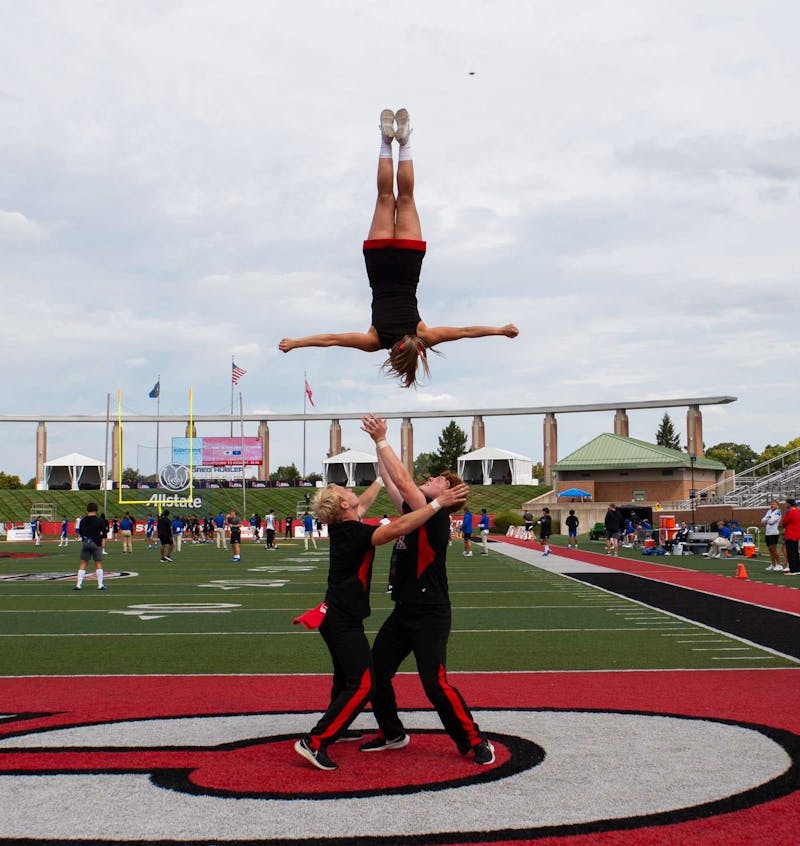 Second-year nursing major Titus Hill (left) and fourth-year communication major Charlie Cronin (right) flip third-year elementary education major Aliya Statler (center) in the air during a routine at the home football game Sept. 16 at Scheumann Stadium. Elyse Timpe, Photo provided