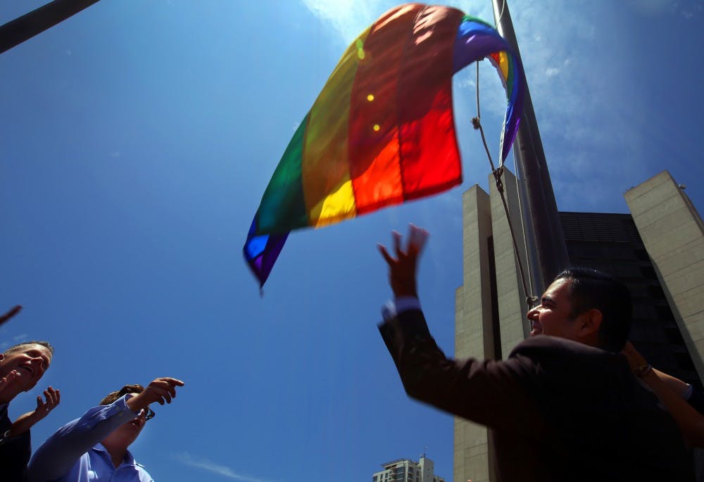 Long Beach, Calif., mayor Robert Garcia, right, the city's first openly gay mayor, raises a Rainbow Pride Flag over the Civic Plaza in response to a U.S. Supreme Court ruling legalizing same-sex marriage on Friday, June 26, 2015. (Rick Loomis/Los Angeles Times/TNS)