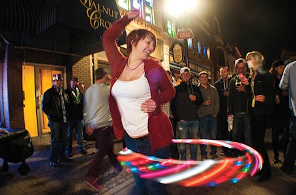 Beth Bickel entertains a crowd with a lit up hula hoop. Different lighted objects from cups, glasses, wands and hula hoops light up the streets during Muncie Gras. DN PHOTO BOBBY ELLIS