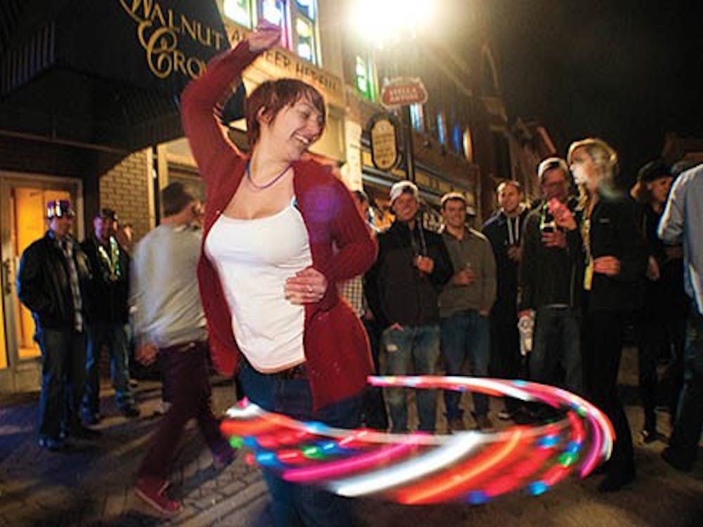 Beth Bickel entertains a crowd with a lit up hula hoop. Different lighted objects from cups, glasses, wands and hula hoops light up the streets during Muncie Gras. DN PHOTO BOBBY ELLIS