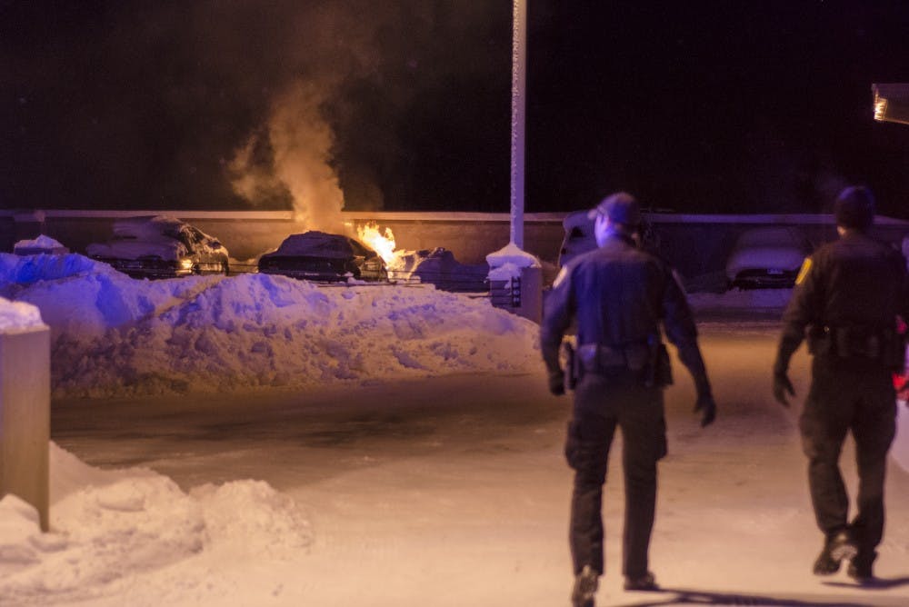 Kyle Kincer's car continues to burn as University Police Department officers clear the area around the top floor of the McKinley Avenue parking garage. The fire began after Kincer locked the keys inside the car and left it running while trying to find help. DN PHOTO COREY OHLENKAMP
