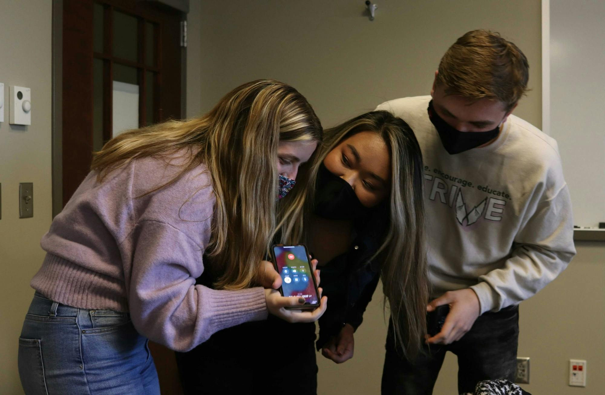 Chiara Biddle, Strive slate vice president elect, Tina Nguyen, president elect, and Joseph Gassensmith, Strive campaign manager, listen to a phone call from Parker Abrell, SGA elections commissioner, March 2, 2021 in a Kinghorn Hall conference room. Abrell called the slate about five minutes after voting closed to congratulate slate members on their win. Rylan Capper, DN