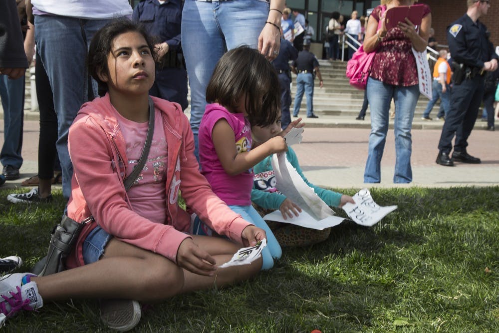 Children sit and peel apart Trump posters while their parents protest at the Donald Trump rally in Indianapolis on April 20. DN PHOTO TRENT SCROGGINS