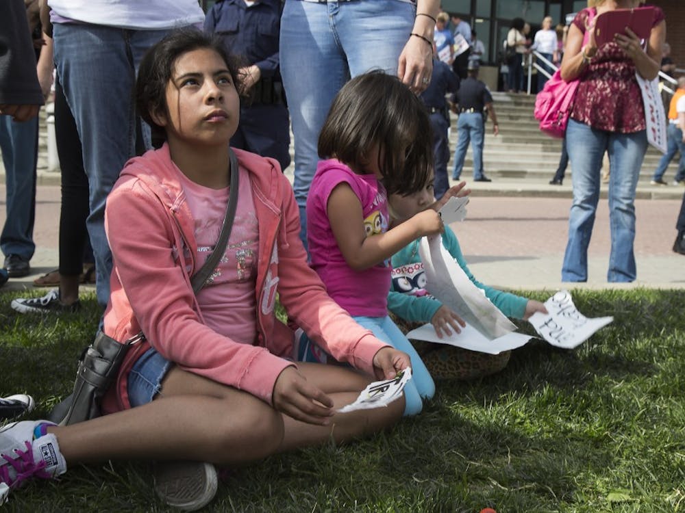 Children sit and peel apart Trump posters while their parents protest at the Donald Trump rally in Indianapolis on April 20. DN PHOTO TRENT SCROGGINS