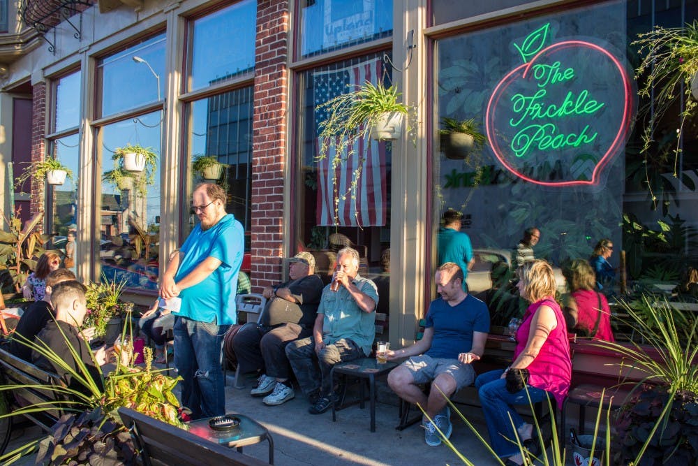 Customers sit on the patio of The Fickle Peach listening to live music by the Tuesday Nite String Band on Sept. 1. The bar and restaurant was one stop in the community event First Thursday, which showcased Muncie’s local artists. Grace Ramey // DN