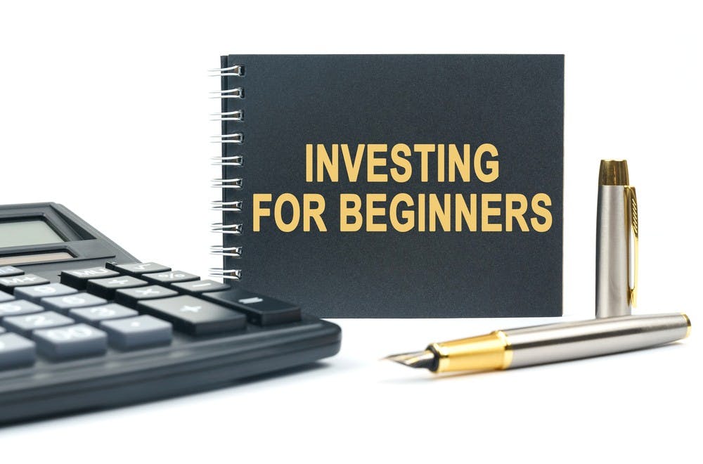 Business and finance. On a white background, there is a calculator, a pen and a black notebook with the inscription - INVESTING FOR BEGINNERS