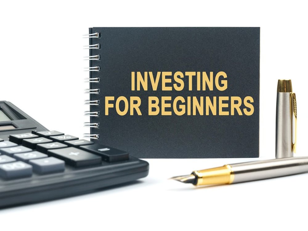 Business and finance. On a white background, there is a calculator, a pen and a black notebook with the inscription - INVESTING FOR BEGINNERS